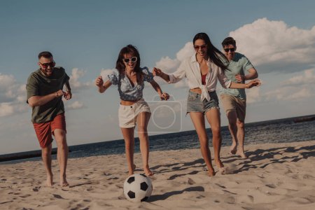 Foto de Grupo de jóvenes jugando al fútbol y divirtiéndose juntos en la playa - Imagen libre de derechos