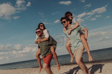 Téléchargez les photos : Groupe de jeunes amis regardant heureux tout en s'amusant sur la plage ensemble - en image libre de droit