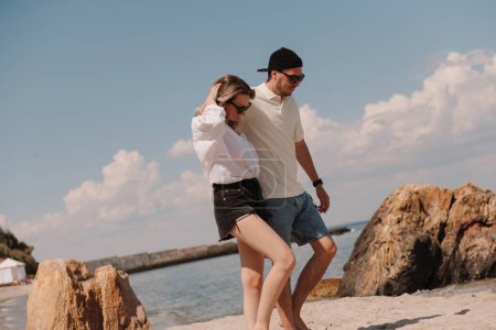 Photo for Beautiful young couple embracing while walking by the beach together - Royalty Free Image