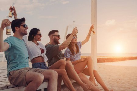 Photo for Group of joyful young people enjoying cold beer while spending fun time on the beach together - Royalty Free Image