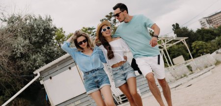 Foto de Tres jóvenes amigos felices pasando tiempo sin preocupaciones mientras caminan juntos por la playa - Imagen libre de derechos