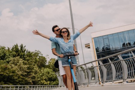 Téléchargez les photos : Beau jeune couple profiter du plaisir ensemble tout en chevauchant scooter électrique à l'extérieur ensemble - en image libre de droit