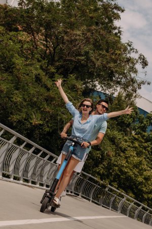 Téléchargez les photos : Heureux jeune couple profiter du plaisir ensemble tout en chevauchant scooter électrique à l'extérieur ensemble - en image libre de droit