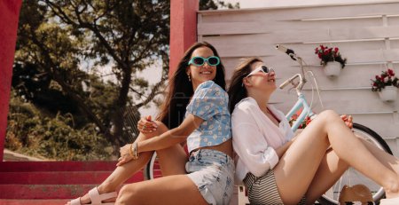 Photo for Two relaxed young women smiling while enjoying summer day outdoors together - Royalty Free Image