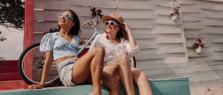 Téléchargez les photos : Deux belles jeunes femmes à la recherche détendue tout en profitant de la journée d'été en plein air ensemble - en image libre de droit