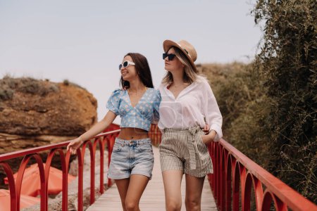 Téléchargez les photos : Deux jeunes femmes à la mode embrassant et souriant tout en marchant à l'extérieur ensemble - en image libre de droit