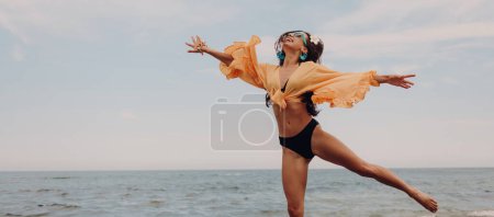 Photo for Joyful young woman in swimwear jumping while enjoying summer day on the beach - Royalty Free Image