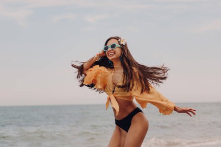 Photo for Attractive young woman in swimwear running and looking happy while enjoying day seaside - Royalty Free Image