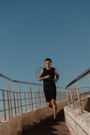 Téléchargez les photos : Athlète masculin confiant en vêtements de sport courant en bas pendant l'entraînement à l'extérieur - en image libre de droit