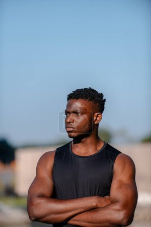 Téléchargez les photos : Beau Africain en vêtements de sport gardant les bras croisés pendant l'entraînement à l'extérieur - en image libre de droit