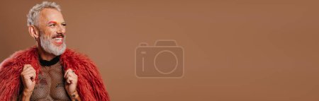 Téléchargez les photos : Gai mature gay l'homme avec arc-en-ciel coloré sourcils portant peluche manteau sur brun fond - en image libre de droit