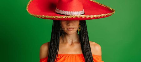 Photo for Gorgeous young Mexican woman in Sombrero standing against green background - Royalty Free Image