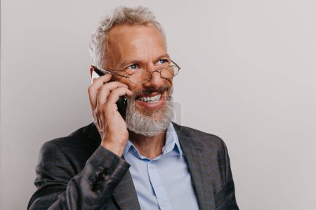 Téléchargez les photos : Portrait d'homme d'affaires mature heureux en coffret textos sur téléphone intelligent sur fond blanc - en image libre de droit