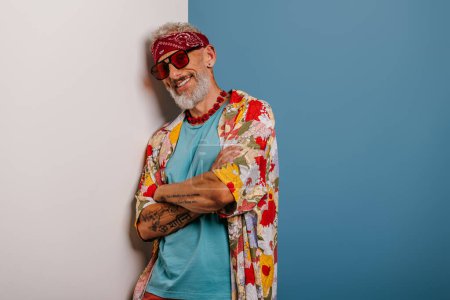 Photo for Happy senior man in stylish funky shirt leaning at copy space while standing against blue background - Royalty Free Image