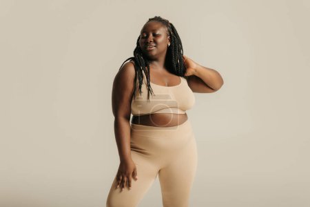 Foto de Atractiva mujer africana con curvas en ropa interior que irradia amor propio en el fondo del estudio - Imagen libre de derechos