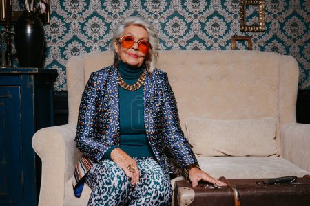 Téléchargez les photos : Belle femme âgée dans le luxe porter rayonnant de confiance et de richesse tout en se relaxant à la maison de style rétro - en image libre de droit