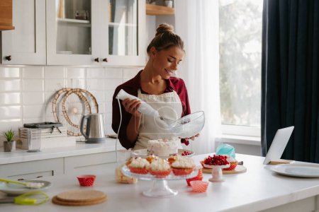 Photo for Confident female confectioner preparing whipped cream while making a cake at the domestic kitchen - Royalty Free Image