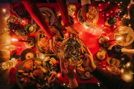 Foto de Vista superior de las personas que disfrutan de una variedad de platos de Navidad mientras cenan en la mesa decorada - Imagen libre de derechos