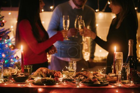 Photo for Beautiful decorated Christmas table with variety of festive dishes and people drinking champagne on background - Royalty Free Image