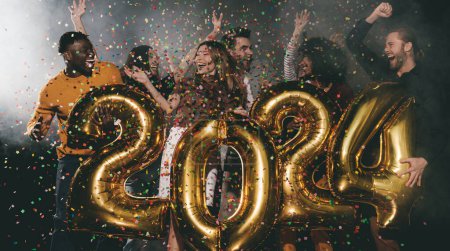 Téléchargez les photos : Groupe de personnes heureuses célébrant 2024 Nouvel An tout en dansant et en jetant des confettis dans une boîte de nuit - en image libre de droit