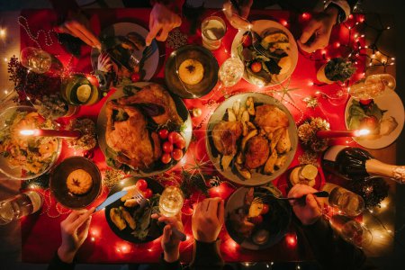 Photo for Top view of people enjoying variety of Christmas dishes while having holiday dinner at the decorated table - Royalty Free Image