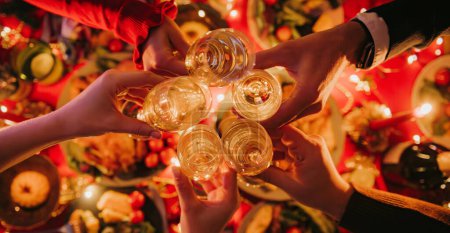 Foto de Vista superior de la gente brindando con champán mientras disfruta de la víspera de Navidad en la mesa de vacaciones decorada - Imagen libre de derechos