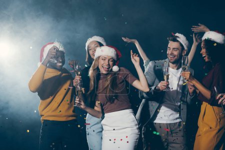 Téléchargez les photos : Groupe de jeunes gens heureux célébrant le Nouvel An en boîte de nuit ensemble tout en confettis volant autour - en image libre de droit