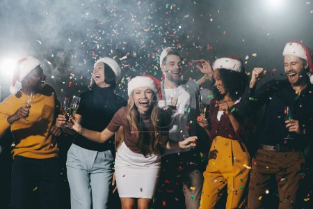 Photo for Happy young people enjoying champagne and dancing while celebrating New Year in night club together - Royalty Free Image