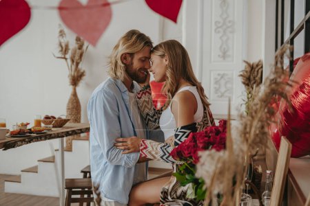 Photo for Young loving couple embracing face to face while celebrating Valentines day at the decorated home - Royalty Free Image
