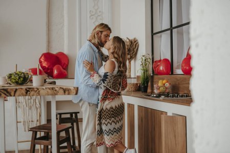 Foto de Romántica pareja joven abrazando y besándose mientras celebra el aniversario de amor en la casa decorada - Imagen libre de derechos