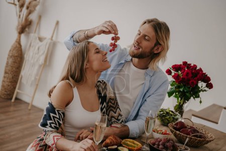 Photo for Playful young loving couple enjoying romantic dinner while celebrating anniversary at home together - Royalty Free Image