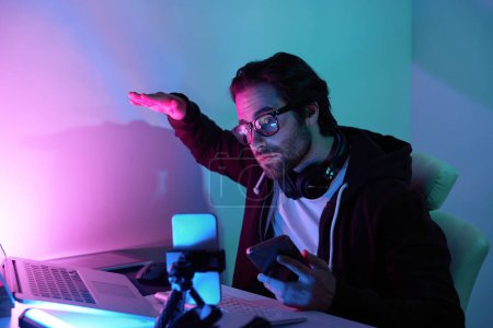 Foto de Hombre joven concentrado utilizando la computadora y streaming en línea contra el fondo colorido - Imagen libre de derechos