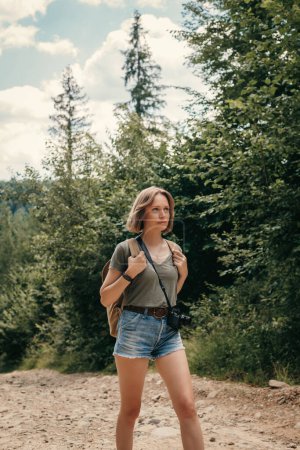 Foto de Hermosa joven viajera con mochila caminando por el sendero de la montaña - Imagen libre de derechos