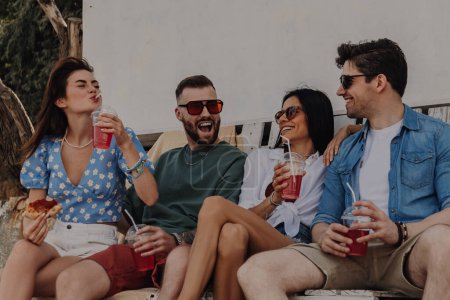Foto de Grupo de amigos felices disfrutando de comida y bebidas mientras pasan tiempo al aire libre juntos - Imagen libre de derechos