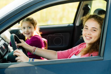 Foto de Little girls having fun in the family's car and looking to the camera. - Imagen libre de derechos