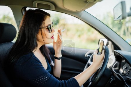 Photo for Driver who is smoking and texting in the same time inside the car. - Royalty Free Image