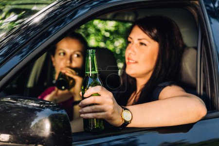 Photo for Two woman are drinking beer while one of them is driver and the car is stopped. - Royalty Free Image