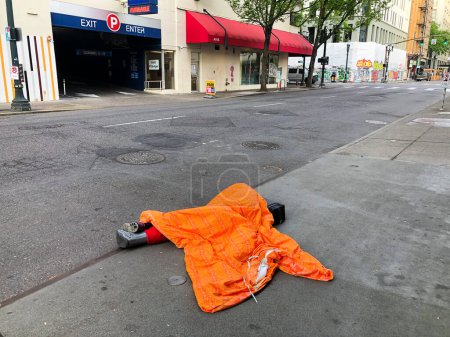 Photo for PORTLAND, OR - MAY 6, 2021: Transient person sleeping under a sleeping bag on the sidewalk showing the drastic homeless epidemic in downtown Portland, OR on May 6, 2021. - Royalty Free Image