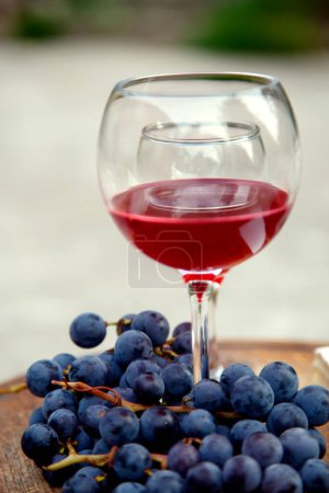 Téléchargez les photos : Des verres avec du vin rouge et un bouquet de raisins. Composition avec du vin rouge dans des verres et un bouquet de raisins. vue de côté, vue de dessus. - en image libre de droit