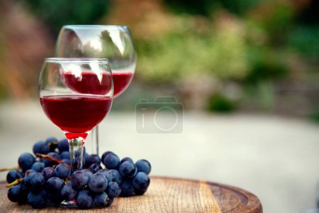 Téléchargez les photos : Des verres avec du vin rouge et un bouquet de raisins. Composition avec du vin rouge dans des verres et un bouquet de raisins. vue de côté, vue de dessus. - en image libre de droit