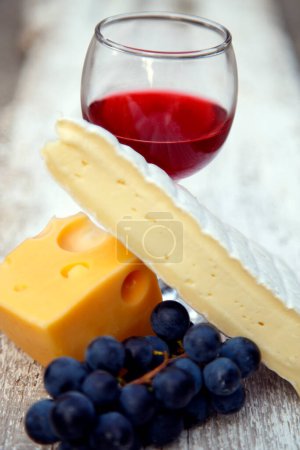 Photo for A glass of red wine in a glass of grapes and cheese. Composition of red wine cheese and grape bunch in the garden. - Royalty Free Image