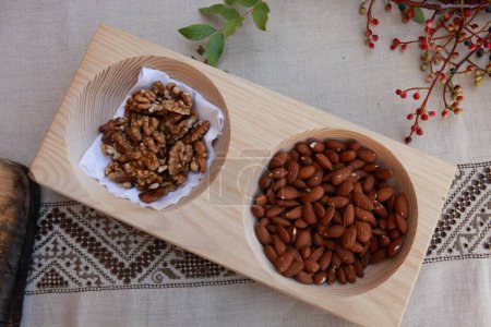 Téléchargez les photos : Amandes rôties et noix dans une assiette en bois sur la table - en image libre de droit