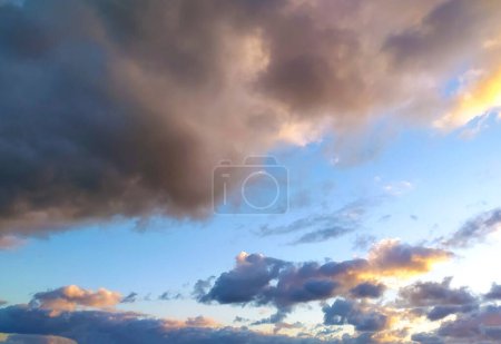 The sun is setting, casting a warm glow over the clouds in the sky. The vibrant colors of the sunset are reflected in the clouds, creating a dramatic and beautiful scene.