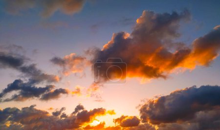 The sun is setting, casting a warm glow over the clouds in the sky. The vibrant colors of the sunset are reflected in the clouds, creating a dramatic and beautiful scene.