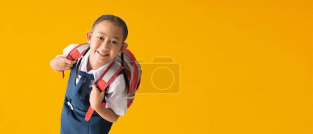 Foto de Back to school banner idea concept, Happy asian school girl in uniform isolated on yellow background, with Clipping paths for design work empty - Imagen libre de derechos