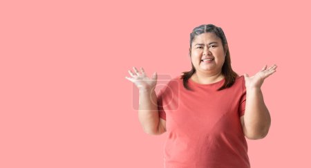 Téléchargez les photos : Fat woman asian show both hands with open palms on upper side with smile face. isolated on pink  background - en image libre de droit