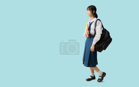 Photo for Full body Asian student girl wearing uniform hold backpack books, isolated on blue background with Clipping paths for design work empty free space - Royalty Free Image