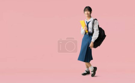 Photo for Full body Asian student girl wearing uniform hold backpack books, isolated on pink background with Clipping paths for design work empty free space - Royalty Free Image