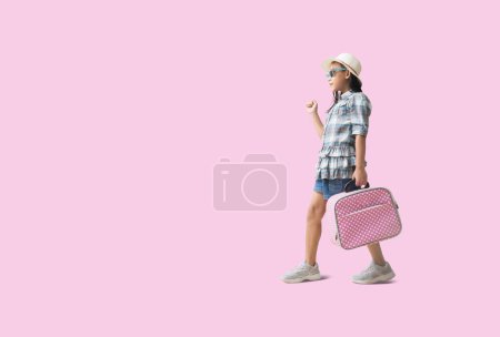 Téléchargez les photos : Pretty asian little girl and hat relaxing  summer vacation travel concept. Smiling cute little girl isolated on pink background with Clipping paths for design work empty free space - en image libre de droit