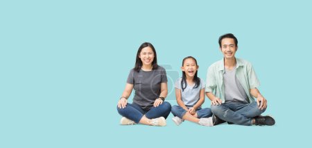 Photo for Happy smiling young asian family sitting on floor have a fun time together, Full body isolated on pastel plain light blue background - Royalty Free Image